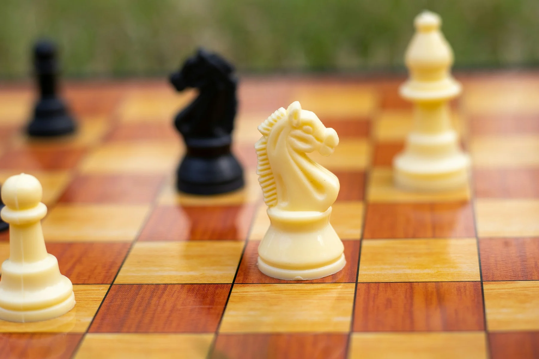 A white knight in focus on a wooden chessboard